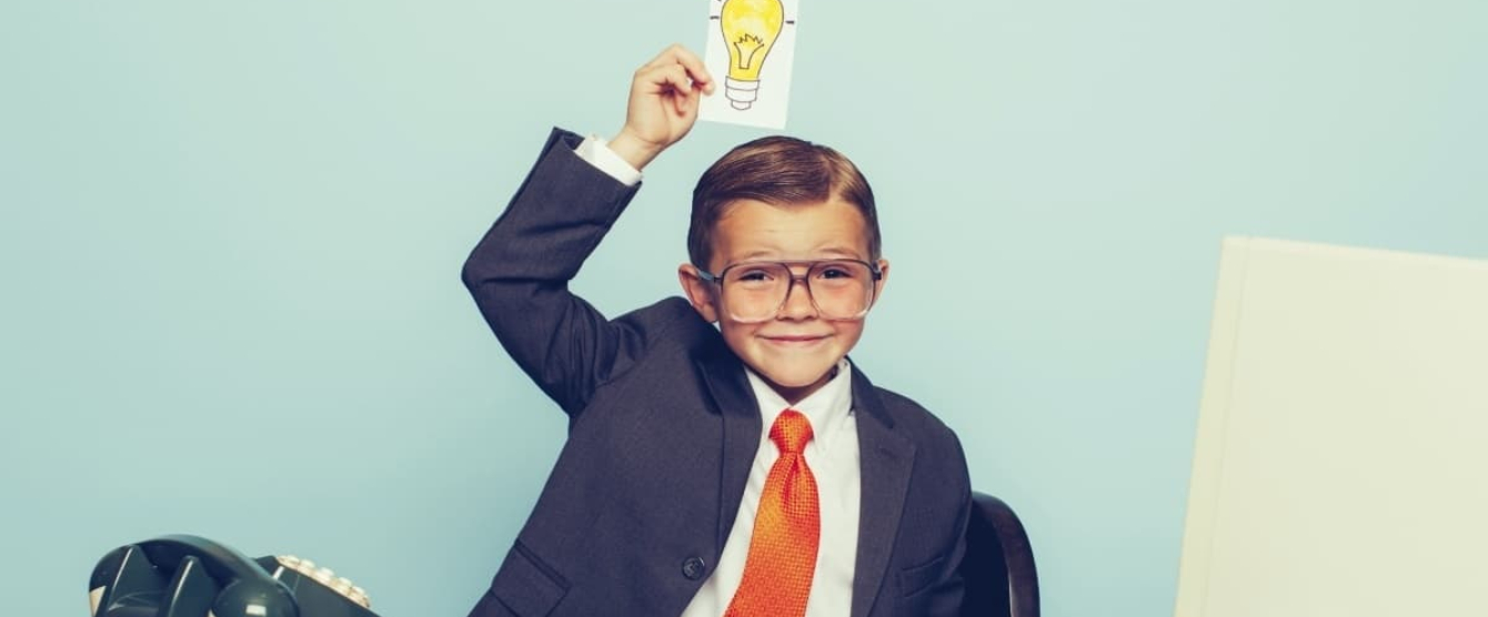 A boy wearing a tie and a shirt holding a picture of a lightbulb over his head