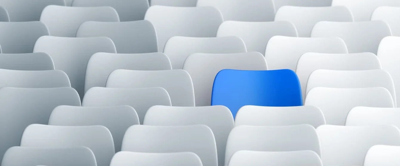 A row of white chairs with one blue chair that stands out