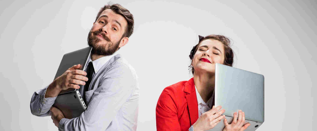 A man and a woman hugging their laptops