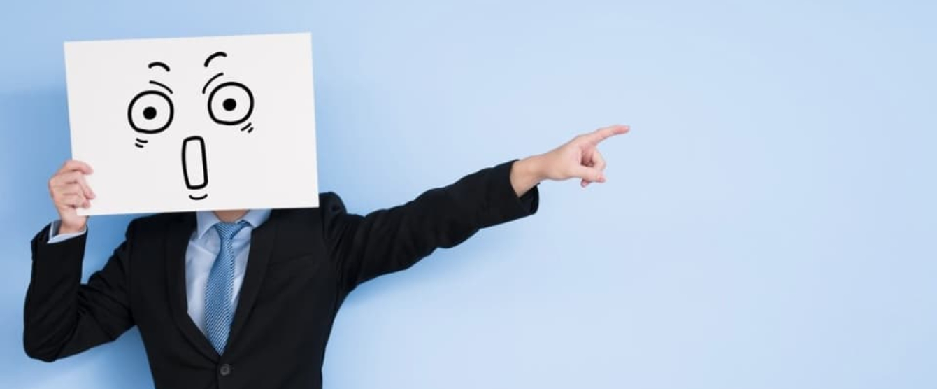 A man holding a sign with a picture of a drawn face