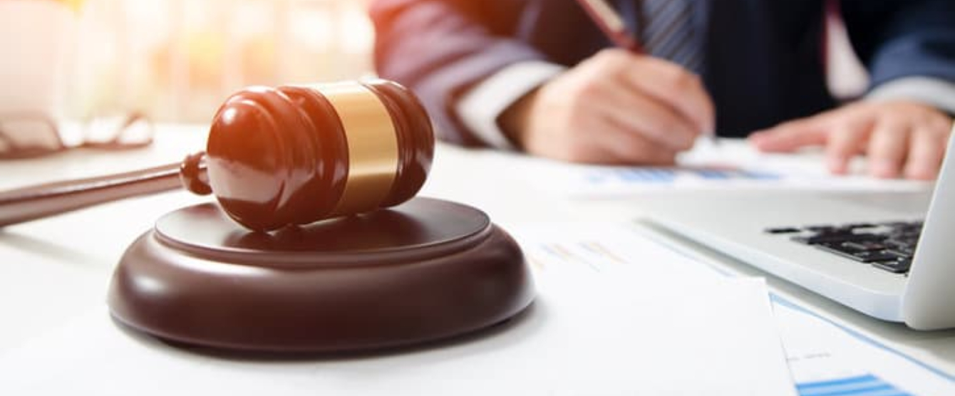 A person writing something on a piece of a paper with a gavel next to him