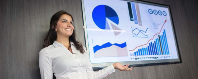 A woman standing in front of a screen giving a presentation