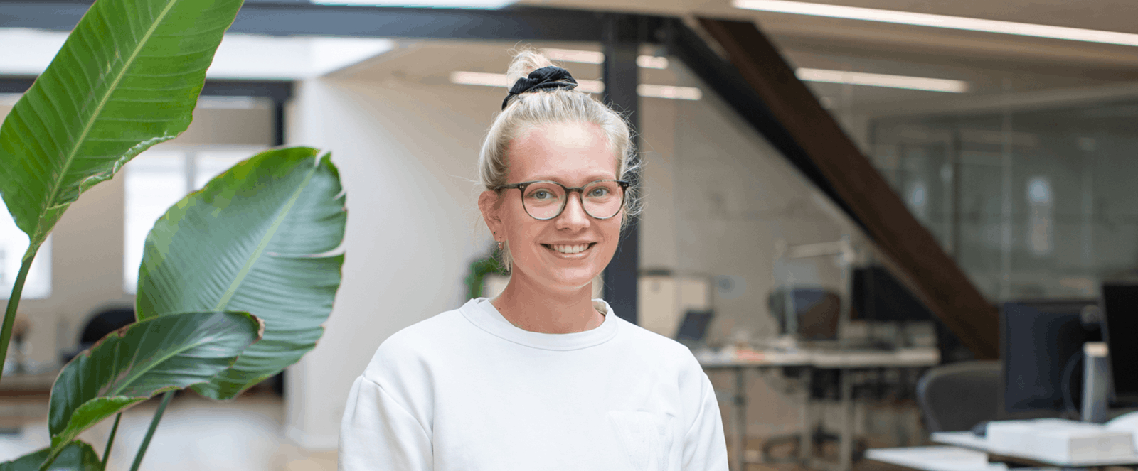 A woman standing next to a plant smiling